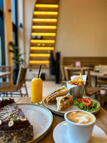a table with two plates of food and a cup of orange juice at Hotel 1920 in Podgorica
