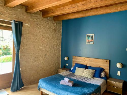 ein Schlafzimmer mit einer blauen Wand und einem Bett in der Unterkunft Domaine de Pech Mortier in Marcillac-Saint-Quentin