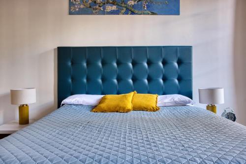 Una cama azul con dos almohadas amarillas. en URBANA 37 Maison, en Roma