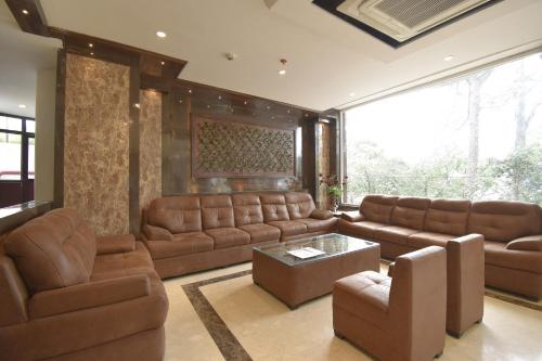 a large living room with brown leather furniture at Sidham Hotel in Jalandhar