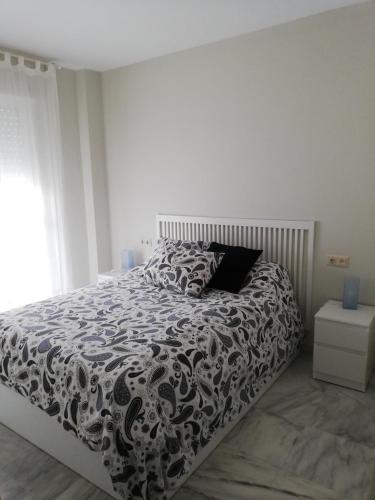 1 dormitorio con 1 cama con edredón blanco y negro en APARTAMENTO EDIFICIO SEVILLA II, en Jerez de la Frontera