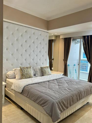 - une chambre avec un grand lit et une grande tête de lit dans l'établissement Belle’s WMR Apartment, à Jakarta