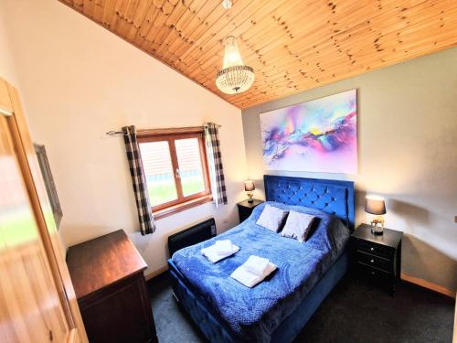 a bedroom with a blue bed and a window at Kingfisher Lodge-HuntersMoon -Warminster-Longleat-Bath in Warminster