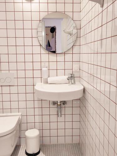 a white tiled bathroom with a sink and a toilet at SLO Hostel Nice in Nice