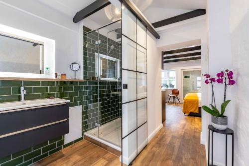 a bathroom with green subway tile and a sink at LÜTTES LOFT Boutique Hotel in Eckernförde