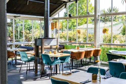 een restaurant met tafels, stoelen en ramen bij Vakantiepark Koningshof in Rijnsburg