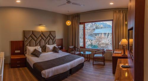 ein Hotelzimmer mit einem Bett und einem großen Fenster in der Unterkunft Hotel The Kargil in Kargil