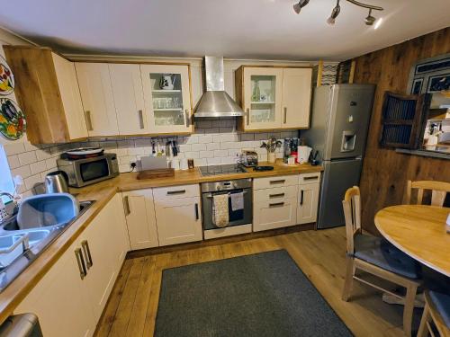 a kitchen with white cabinets and a table in it at Pitcaithly Cottage in Abernethy