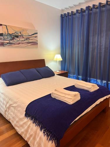 a bedroom with a large bed with blue curtains at Apartamento Vitória in Praia da Vitória