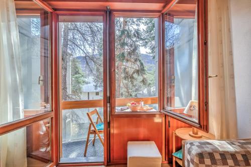 una camera con finestre in vetro, tavolo e sedia di Slalom 73 - Happy Rentals a Bardonecchia