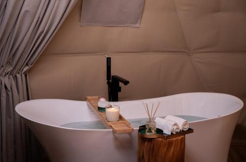 a bath tub with a candle and towels in a bathroom at PAUSEAWAY at Tuwaiq House in Riyadh