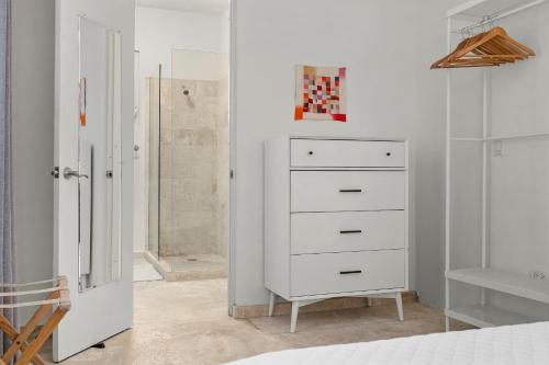 a bedroom with a white dresser and a bathroom at Seaside Caribbean Comfort - Between Beach and City in San Juan