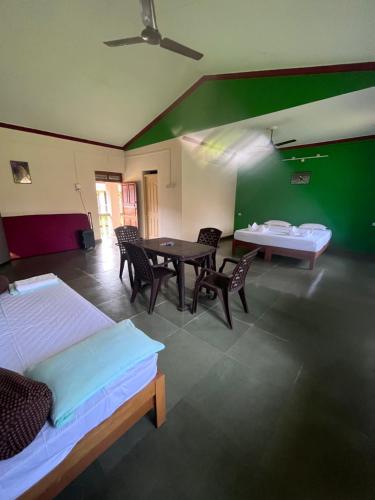 a room with two beds and a table and chairs at Green valley jungle resort in Pernem