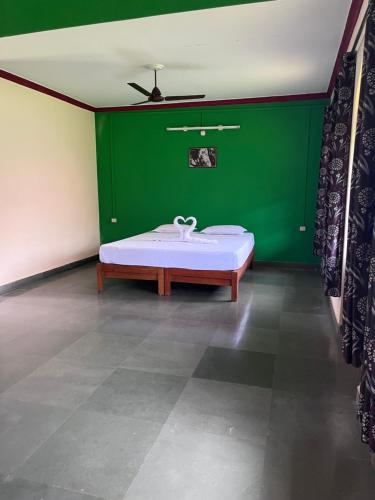 a green room with a bed and a green wall at Green valley jungle resort in Pernem