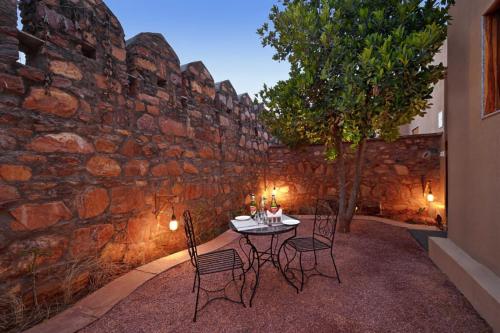 a table and chairs in front of a stone wall at RANTHAMBORE SAFARI BOOKING in Sawāi Mādhopur