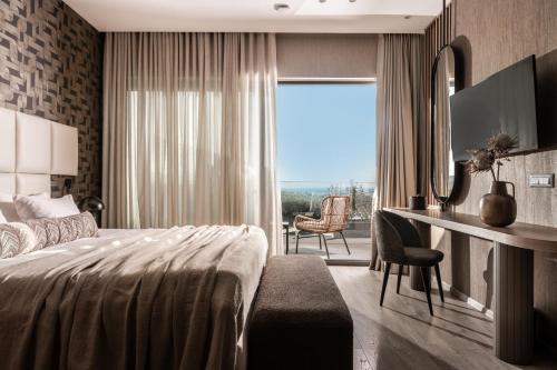 a bedroom with a bed and a desk with a window at Elegance Luxury Executive Suites - Adults Only in Tragaki