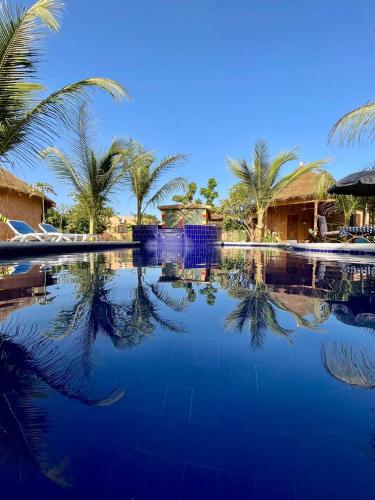 una piscina con palmeras y un edificio en Sulcata Lodge en Ouoran