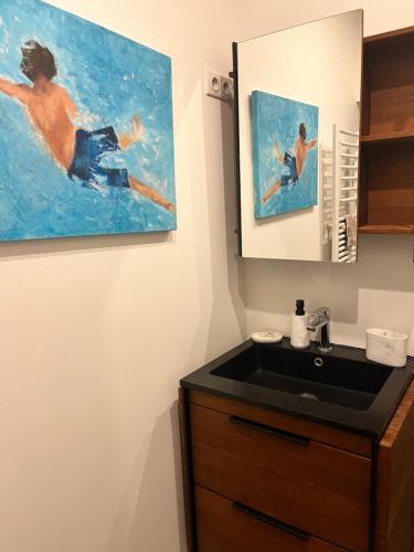 un baño con lavabo y una pintura en la pared en Chambre d hôte - Bambou en Saint-Maur-des-Fossés