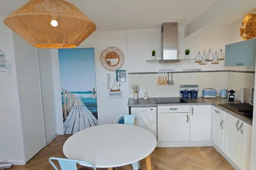 eine Küche mit weißen Schränken, einem Tisch, einem Tisch und Stühlen in der Unterkunft BERCK Beach Attitude 160 QUEEN SIZE très confort - 3min de la plage in Berck-sur-Mer