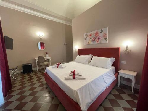 a bedroom with a large bed with white sheets and red decorations at B&B Romeo Luxury Rooms in Catania