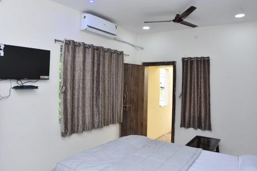 a bedroom with a bed and a tv on the wall at AATITHYA HOME STAY in Ujjain