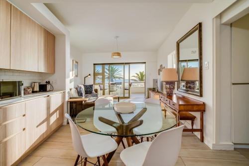 cocina y comedor con mesa de cristal y sillas blancas en Sundowner Views, en Ciudad del Cabo