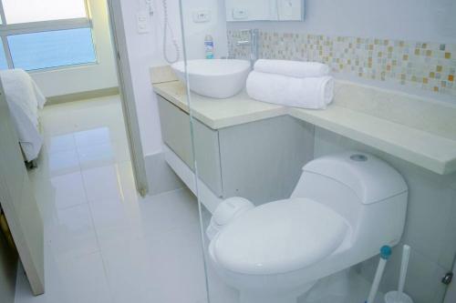 a white bathroom with a toilet and a sink at Apartament Bocagrande Palmetto Beach Front 3204 in Cartagena de Indias