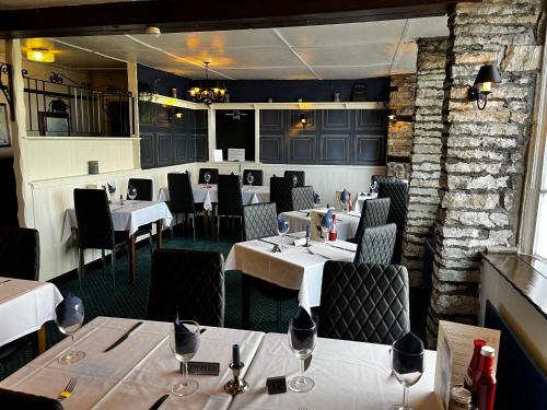 uma sala de jantar com mesas e cadeiras brancas em Black Bull Hotel em Reeth