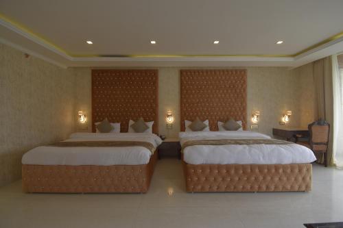 twee bedden in een hotelkamer met verlichting aan de muur bij Dalhousie Hotel & Resort in Dalhousie