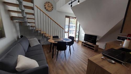 a living room with a couch and a table and a clock at APARTAMENT BULWAR PRZY PLAŻY - 100m od plaży in Krynica Morska