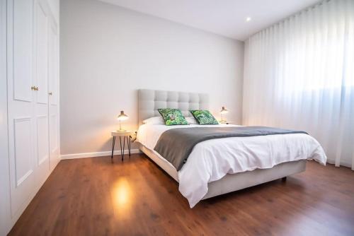 a white bedroom with a large bed with green pillows at Cozy Sea View by CITADINE in Ponta Delgada
