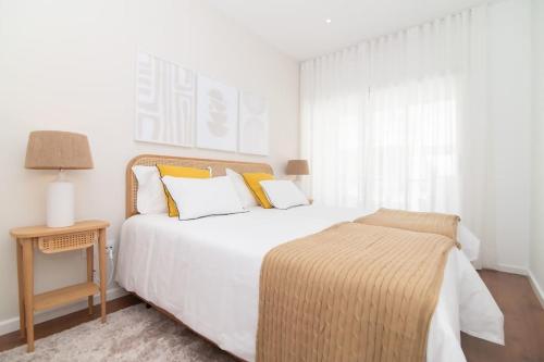 a bedroom with a white bed with yellow pillows at Cozy Sea View Apartment near City and Airport in Ponta Delgada