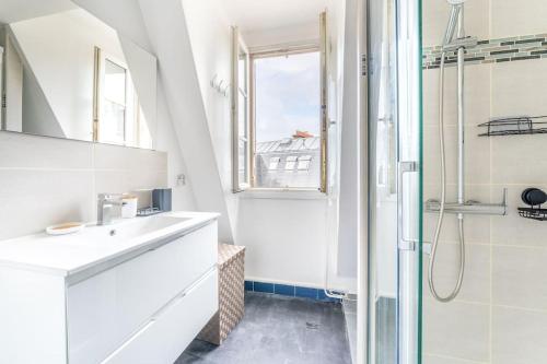 une salle de bain blanche avec un lavabo et une douche dans l'établissement Charmant Appartement Proche Tour Eiffel, à Paris