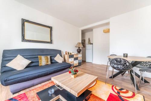 un salon avec un canapé bleu et une table dans l'établissement Charmant Appartement Proche Tour Eiffel, à Paris