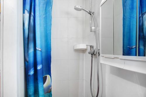 La salle de bains est pourvue d'une douche avec un rideau de douche bleu. dans l'établissement Milchtütenzimmer - Upcycling, à Grünwald