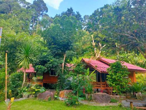 una casa con techo rojo en un bosque en ท่าเเพ รีสอร์ท en Ban Tha Phae