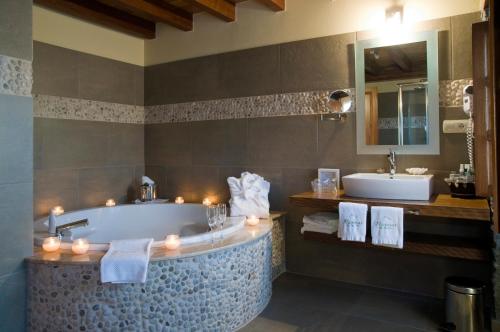 een badkamer met een bad en een wastafel met kaarsen bij Hotel Pleamar in Puerto de Vega