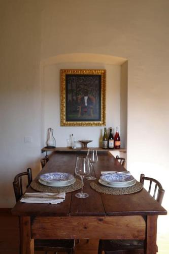 a wooden table with two plates and wine glasses at Apartamento en Casa del Siglo XVI con caballos in Ametlla