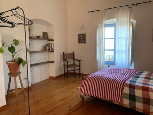 a bedroom with a bed and a chair and a window at Apartamento en Casa del Siglo XVI con caballos in Ametlla