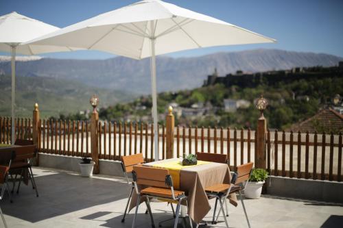 a patio with a table and chairs and an umbrella at Guest House Juald in Gjirokastër