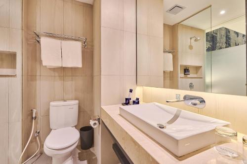 a white bathroom with a toilet and a sink at Aston Sorong Hotel & Conference Center in Sorong