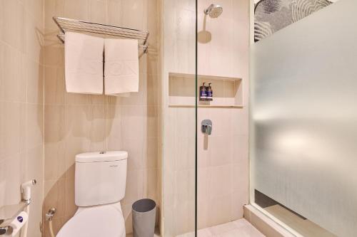 a bathroom with a toilet and a glass shower at Aston Sorong Hotel & Conference Center in Sorong
