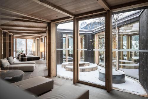 een woonkamer met glazen ramen en een bank bij Adler Spa Resort Dolomiti in Ortisei