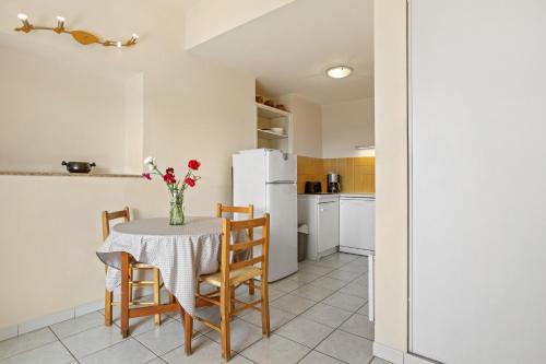een keuken met een tafel met stoelen en een witte koelkast bij Le Mas Berliat N°7 in Bormes-les-Mimosas
