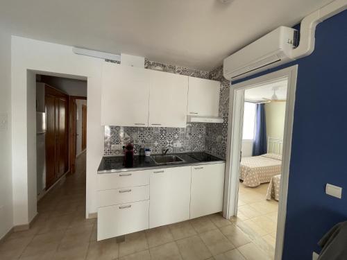una cucina con armadi bianchi e lavandino di Mitjaneta Apartamento con piscina a Cala en Blanes