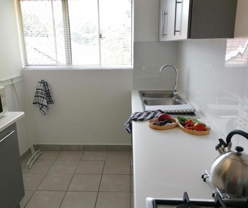 uma cozinha com um balcão com um lavatório e alguns vegetais em @946 em Pretoria