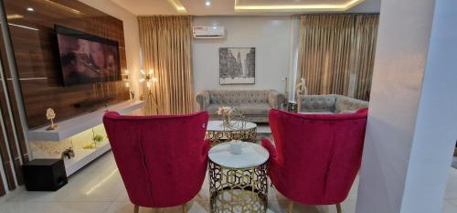 a living room with red chairs and a table at Luxury 3-Bed house in gated estate with pool Lekki in Maiyegun