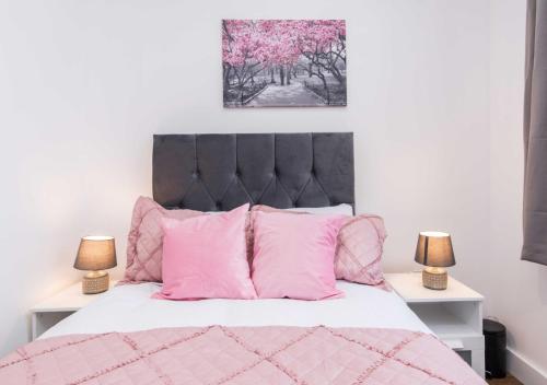 a bedroom with a bed with pink pillows at Webberley Stylish and Spacious Studio Unit in Stoke on Trent in Stoke on Trent