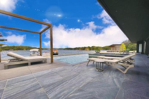 a wooden deck with a table and benches on the water at MOKU ISESHIMA ーl モク伊勢志摩 lー in Shima