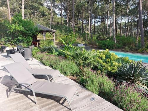 - une rangée de chaises longues assises sur une terrasse près de la piscine dans l'établissement Entre Océan et Lac, vue sur le golf, à Lacanau